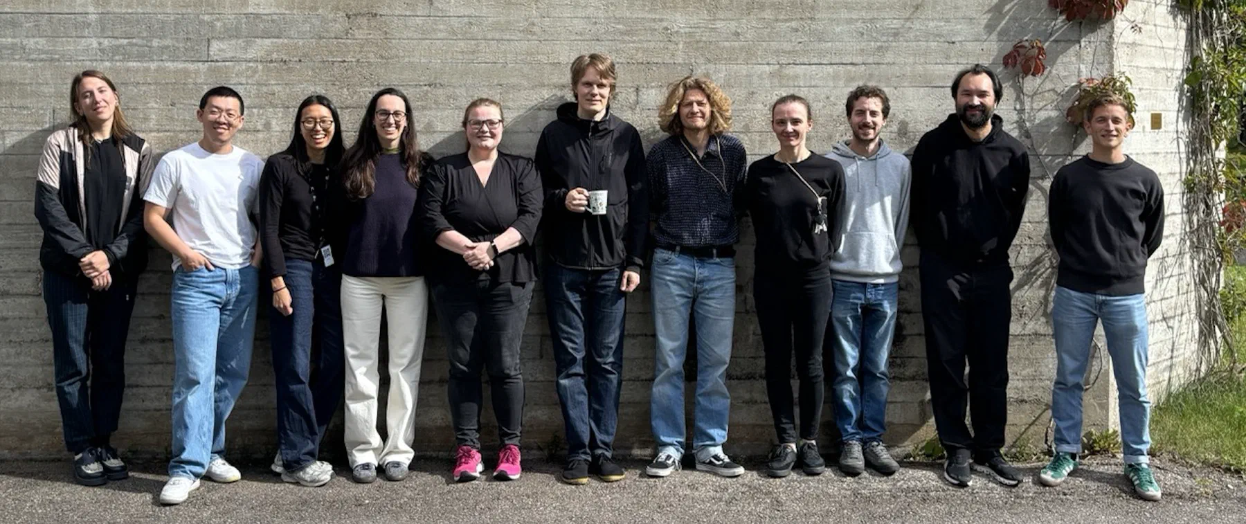 The Artificial Audio group standing in a row in front of a concrete wall